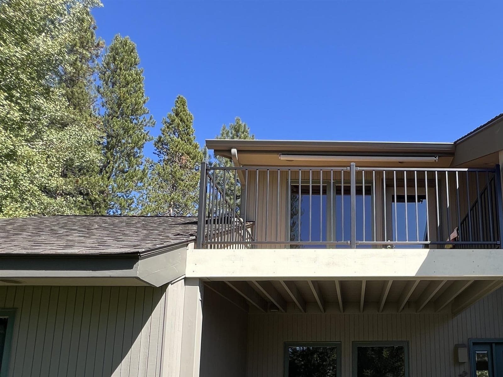 Elevated Central Oregon balcony with a metal picket guard rail above a covered patio