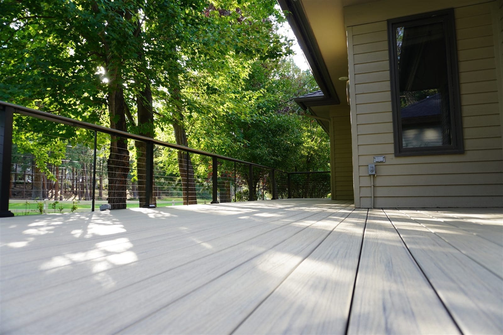 Composite deck with horizontal cable railing overlooking trees in Central Oregon